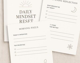 May include: A set of printable mindset journals with prompts for daily and evening reflection. The journals feature minimalist designs with sun, moon, and floral illustrations. The text includes "Daily Mindset Reset", "Morning Focus", and "Evening Reflection".