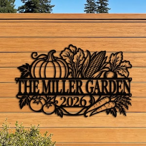 Puede incluir: Un letrero de pared de metal negro con un diseño recortado de una calabaza, maíz, verduras de hoja, tomates y zanahorias. El texto dice THE MILLER GARDEN y 2026. El letrero tiene una barra horizontal que separa el texto de las ilustraciones.