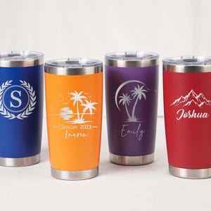 May include: Four stainless steel tumblers in blue, orange, purple, and red. Each tumbler has a silver lid and features a unique design: a monogram, a beach scene, palm trees, and mountains with a name.