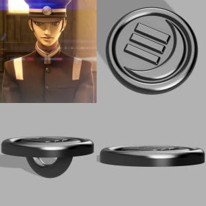 Puede incluir: Un botón negro con un diseño circular que presenta tres líneas horizontales y una forma de media luna. El botón tiene un lazo en la parte posterior para coser. La imagen también muestra a una persona con uniforme oscuro y sombrero.