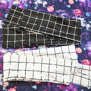 May include: Two black and white checkered fabric leg warmers. One pair is black with white stripes and the other is white with black stripes.