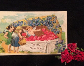 Valentine Postcard - Girl and Boy - Cupid selling Hearts - Violets - Antique Postcard