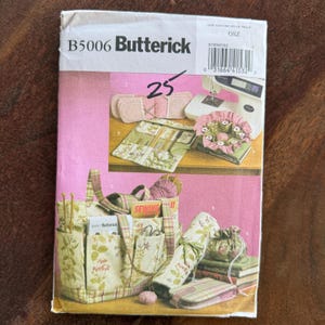 May include: A pink and white Butterick sewing pattern envelope with the number 25 in black. The envelope features images of sewing projects, including a tote bag, needle case, and sewing machine. The tote bag has a floral pattern.