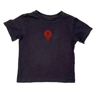 Könnte beinhalten: Ein dunkelblaues T-Shirt mit einem roten Standort-Pin-Grafik auf der Brust. Das kurzärmelige Shirt ist aus einem weichen Material gefertigt und eignet sich für Freizeitkleidung. Das Design ist einfach und auffällig.