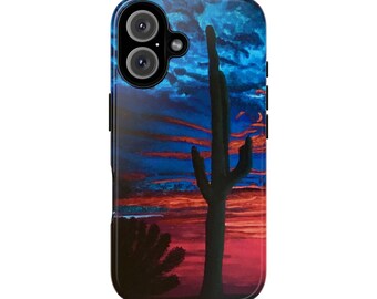 May include: A phone case with a desert landscape painting. The design features a silhouetted saguaro cactus against a vibrant sunset sky with red, orange, and blue hues. The case has a glossy finish and a camera cutout.