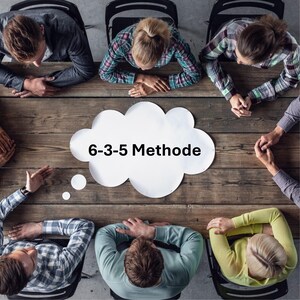 May include: An overhead shot of a group of people seated around a wooden table. A white cloud-shaped thought bubble with the text "6-3-5 Methode" is in the centre. People are wearing casual clothing.