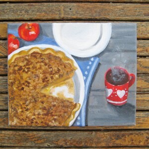 Op de afbeelding: Een schilderij van een taart met een bruine korst en een witte vulling, twee rode appels, een wit bord en een rode mok met witte hartjes op een grijze achtergrond.