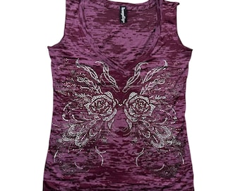 May include: A sleeveless, deep burgundy top with a V-neck. The front features a sparkling, rhinestone design of two roses and wing-like accents. The fabric has a textured, semi-sheer appearance. The tag reads "Sangria Sky".