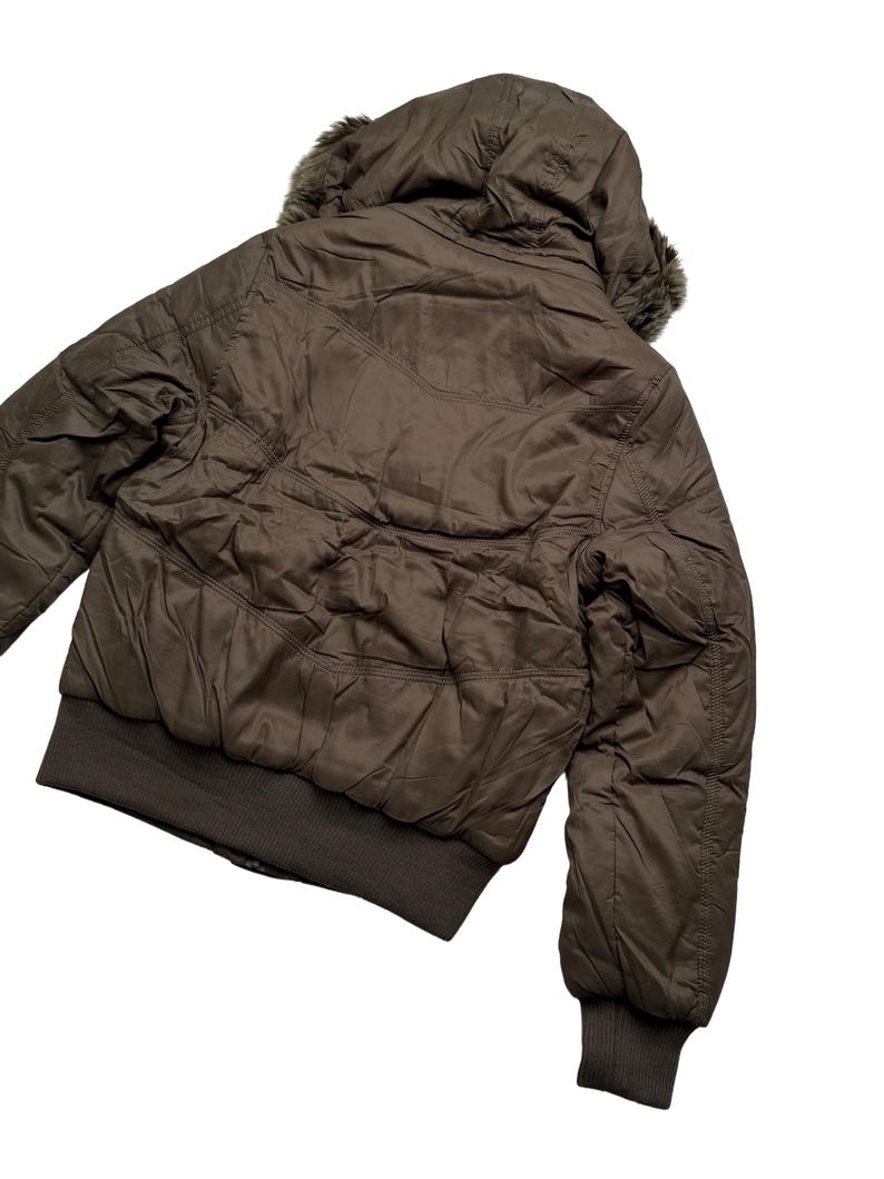 May include: A brown bomber jacket with a hood and faux fur trim. The jacket has a quilted design and a ribbed hem and cuffs. The jacket is shown from the back, with the hood up.