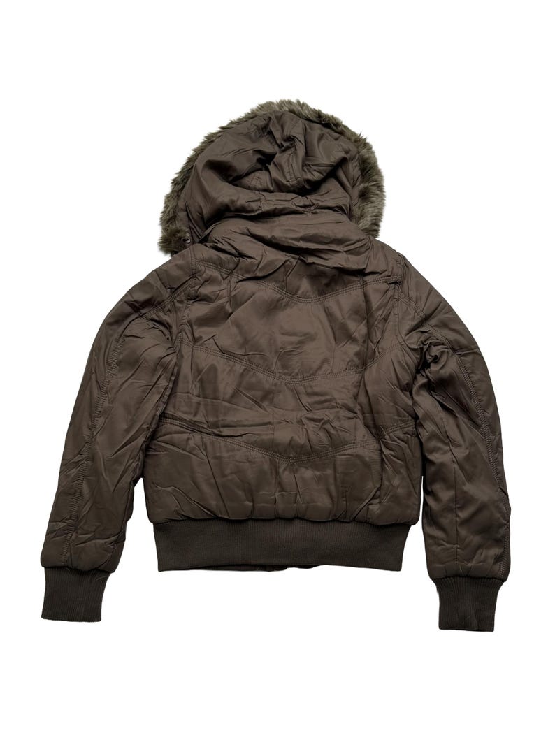 May include: A brown bomber jacket with a faux fur-lined hood. The jacket has a ribbed hem and cuffs. The back of the jacket is visible, showing the quilted design. The jacket is a solid brown color.