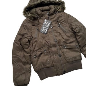 May include: Brown bomber jacket with a hood trimmed with faux fur. The jacket has multiple pockets, a zipper closure, and a ribbed hem and cuffs. A tag with the text "Enlai Fashion" is attached.