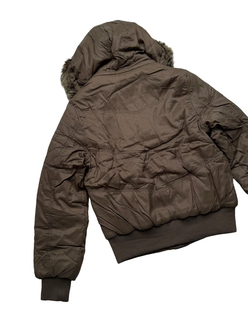 May include: A brown bomber jacket with a hood and faux fur trim. The jacket has a ribbed hem and cuffs. The jacket is made of a quilted material and has a zipper closure. The jacket is a neutral color and can be worn in the fall or winter.