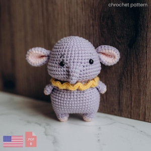 May include: A handmade crochet elephant in lavender with a yellow ruffled collar. The elephant has large, pink-lined ears and small black eyes. The text "chrochet pattern" is visible in the upper right corner.