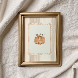 May include: A rectangular gold frame containing a print with a vertical striped background. The print features a central orange pumpkin illustration enclosed within a decorative rectangular border with ornate corner details and thin line accents.