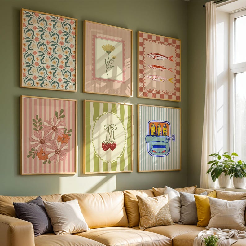 May include: A gallery wall arrangement of six rectangular framed art prints featuring various illustrations including floral patterns, a single flower, fish, a bouquet of daisies, two cherries, and a tin of sardines, all displayed in light wood frames.