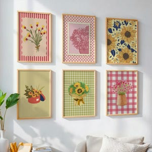 May include: A set of six rectangular wall art prints in light wooden frames. The prints feature various floral arrangements, including sunflowers and wildflowers, set against backgrounds with red stripes, pink checkered patterns, and green gingham.