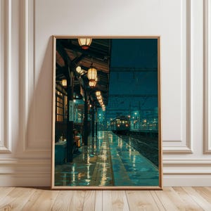 May include: A framed art print depicts a rainy train station scene. The artwork features a long platform with a train in the distance, illuminated by warm-toned lanterns. The wet platform reflects the lights, creating a moody, atmospheric aesthetic.