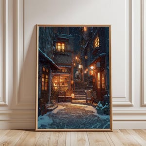May include: A framed print depicts a snowy street scene at night. Buildings with warm, inviting lights line the cobblestone street. Snow falls gently, creating a cozy, wintery atmosphere. The artwork is framed in a light brown wooden frame.
