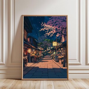 May include: Framed art print depicting a nighttime Japanese street scene. The artwork features a cobblestone street lined with shops and lanterns. Cherry blossoms bloom overhead under a starry sky. The print is in a wooden frame.