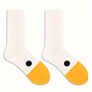 May include: A pair of white socks with yellow toes and a black dot on the side. The socks are made of a soft material and are designed for comfort and style. The socks are a fun and playful accessory.