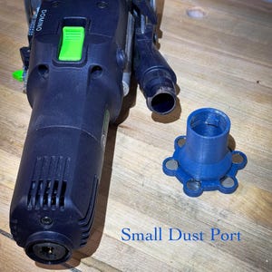 May include: A dark blue power tool with green accents and the word "DOMINO" printed on the side. A blue small dust port is next to the tool. The text "Small Dust Port" is printed in blue.