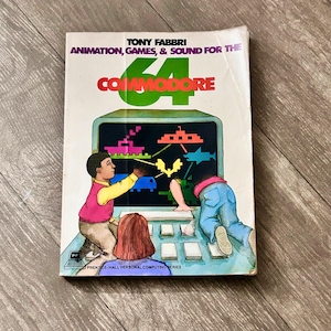 Puede incluir: Un libro de tapa blanda titulado Animation, Games, & Sound for the Commodore 64 de Tony Fabbri. La portada presenta una ilustración colorida de dos personas interactuando con una pantalla de computadora que muestra gráficos pixelados.