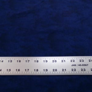 May include: Dark blue fabric with a textured appearance. A metal ruler with inch measurements is across the bottom. The ruler reads up to 25 inches and has the text "MADE IN U.S."