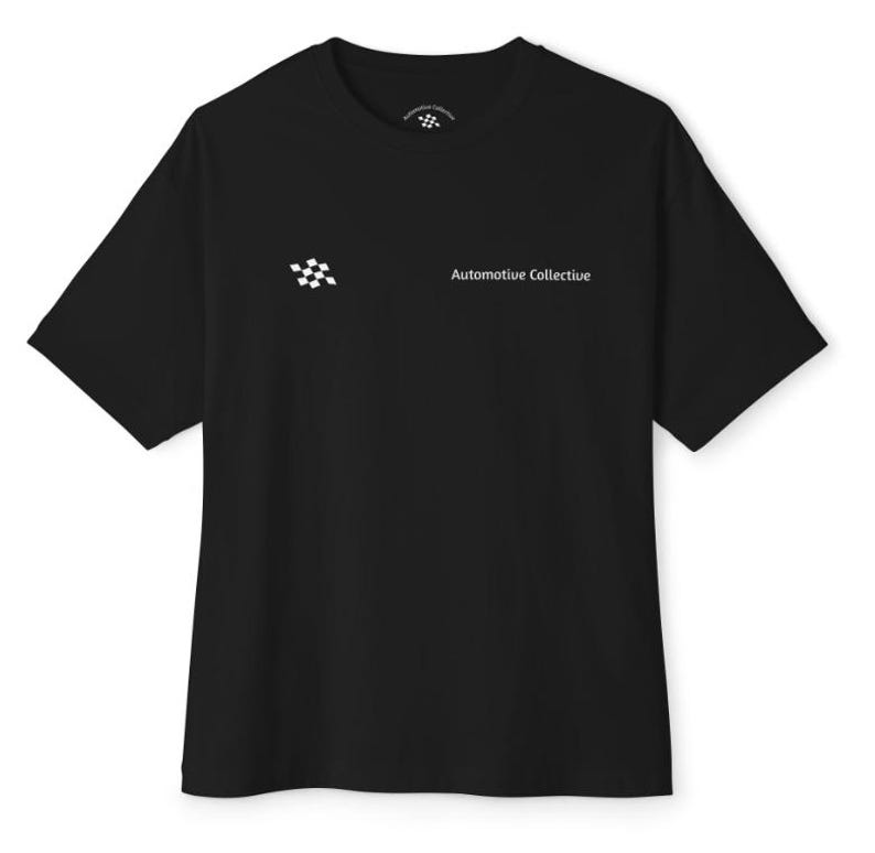 May include: A black short-sleeve t-shirt featuring a small white checkered flag icon and the text "Automotive Collective" printed on the left chest. The inner neck label also displays a small matching checkered flag logo.