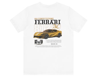 May include: White t-shirt featuring a gold Ferrari 812 Competizione graphic. The design includes the text "FERRARI 812 AC" and "00:05:10". The shirt has a classic crew neck and short sleeves.