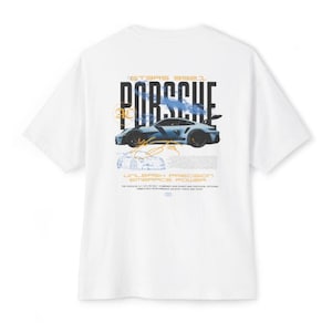 May include: A white t-shirt featuring a graphic on the back with the text PORSCHE, GT3RS 992.1, UNLEASH PRECISION EMBRACE POWER. The design includes a blue sports car illustration, technical line drawings, and orange accents.