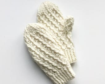 May include: A pair of ivory-colored knitted mittens. The mittens have a textured pattern and are made of a thick yarn. The background is a plain white surface. These mittens are designed for warmth and comfort.
