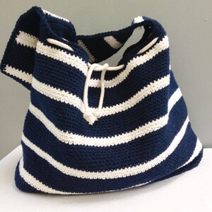 May include: A navy blue and white striped crocheted tote bag with a drawstring closure.