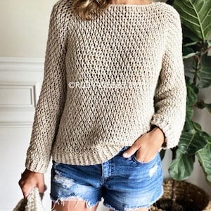 May include: A beige crochet sweater with a loose fit and long sleeves. The sweater has a simple, open stitch pattern.