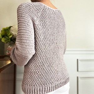 May include: A light purple crocheted sweater with a v-neck and long sleeves.
