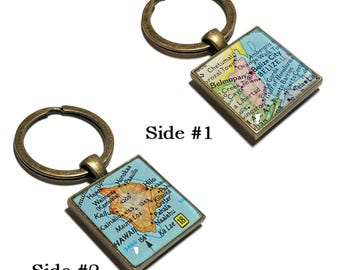 Puede incluir: Dos llaveros cuadrados con anillos de color bronce. Un llavero presenta un mapa de Belice, el otro un mapa de Hawái. Los mapas están enmarcados en un marco cuadrado de color bronce. El texto "Side #1" y "Side #2" está impreso en la imagen.