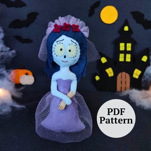 May include: A felt doll resembling a character from a Tim Burton film, wearing a purple dress and veil, with blue skin and hair. The background includes a black haunted house, bats, and a pumpkin. A white circle with "PDF Pattern" is in the image.