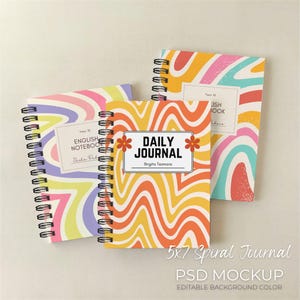 May include: Three spiral-bound notebooks with colorful, wavy patterns in yellow, orange, pink, and blue. The central notebook reads "DAILY JOURNAL" with the name "Brigita Tsamara." The notebooks are 5x7 inches.