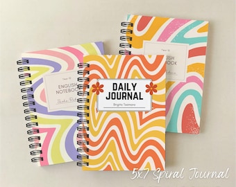 May include: Three spiral-bound notebooks with colorful, wavy patterns in yellow, orange, pink, and blue. The central notebook reads "DAILY JOURNAL" with the name "Brigita Tsamara." The notebooks are 5x7 inches.