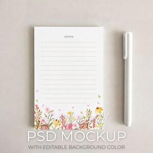 May include: A white notepad with lined pages and the word "NOTES" at the top. The bottom of the notepad features a watercolour floral design in pink, yellow, and green. A white pen rests beside the notepad. The text "PSD MOCKUP" is at the bottom.
