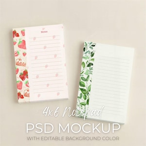 May include: Two 10 x 15 cm notepads. One notepad has a strawberry design with the word "Notes". The other notepad has a green leaf design. The text "4x6 Notepad PSD MOCKUP WITH EDITABLE BACKGROUND COLOR" is at the bottom.