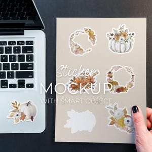 May include: A mockup featuring several fall-themed stickers with floral and pumpkin designs. The stickers are arranged on a beige background, with a laptop and a hand holding the paper. The text "Sticker Mockup with Smart Object" is visible.