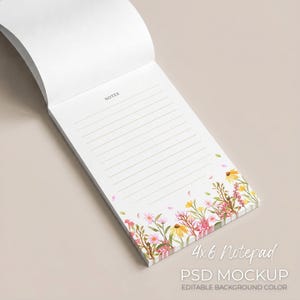 Op de afbeelding: Een witte notitieblok met gelinieerde pagina's en een bloemenrand met roze, gele en groene aquarelbloemen. Het notitieblok heeft de tekst "NOTES" bovenaan en "4x6 Notepad" onderaan.