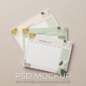 May include: Three monthly planners in beige, green, and white, with abstract botanical designs. Each planner has a calendar grid, a section for monthly goals, and the text "Monthly planner." The size is 27.9 x 21.6 cm. The text "PSD MOCKUP" is also visible.