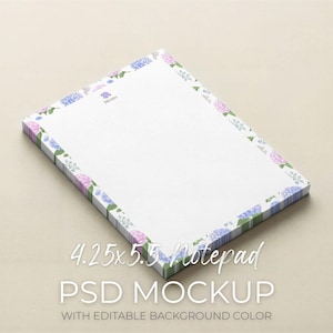 May include: A rectangular notepad with a floral border featuring blue and purple hydrangeas. The notepad measures approximately 10.8 x 14 cm. The word "Memo" is printed at the top, and the text "4.25x5.5 Notepad PSD Mockup with Editable Background Color" is at the bottom.
