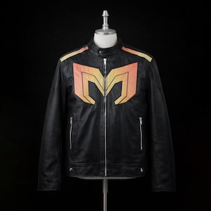 Puede incluir: Chaqueta de cuero negra con cuello alzado y cremallera frontal. La chaqueta presenta un gran gráfico estilizado naranja y amarillo en el pecho y detalles en los hombros. Dos bolsillos con cremallera son visibles en la parte delantera.