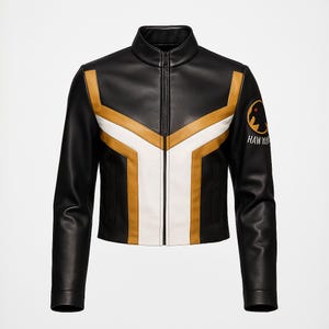 Pode incluir: Casaco de couro preto com gola alta e zíper completo. O casaco apresenta detalhes geométricos dourados e brancos na frente e nos ombros. Um patch circular com um gráfico e o texto "HAWK" está na manga esquerda.