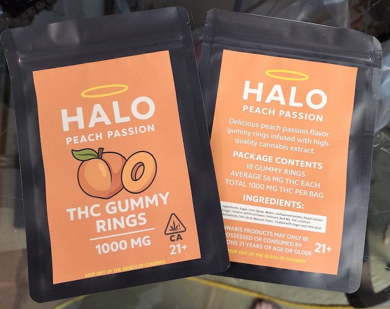 May include: Two black resealable pouches with orange labels. The front label reads HALO PEACH PASSION THC GUMMY RINGS 1000 MG with a peach graphic. The back label lists 18 gummy rings, 56 mg THC each, 1000 mg total, ingredients, and a 21+ warning.