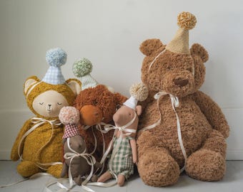 May include: A collection of plush teddy bears and animal figures, each adorned with party hats and ribbons. The bears are various shades of brown and gold, with soft textures and whimsical details, perfect for a child's room.
