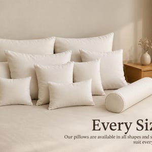 Puede incluir: Una colección de cojines de color crema en varias formas y tamaños, incluyendo estilos cuadrados, rectangulares y cilíndricos, dispuestos sobre una cama. El texto "Every Size" y "Our pillows are available in all shapes and sizes to suit every need" es visible.