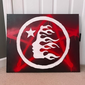 May include: A rectangular canvas painting featuring a black background with a large red spray-painted star. Centered is a white circular border enclosing a white silhouette of a human profile with hair depicted as flames and a small white star.
